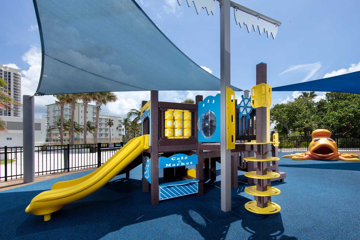 Shaded shipwreck themed playground with play panels, climbers, and slides.